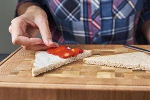 mulher cozinhando torradas de sanduíches com bagas frescas na cozinha foto