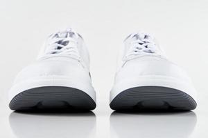 par de tênis masculino branco sobre fundo branco isolado foto
