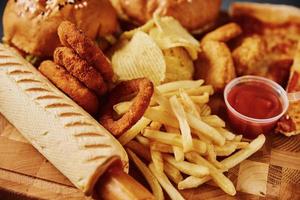 comida insalubre e lixo. diferentes tipos de fast food na mesa, closeup foto