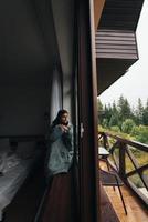 mulher senta-se no parapeito da janela e olha para as montanhas foto