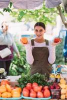 jovem vendedora segurando tomates caseiros nas mãos foto