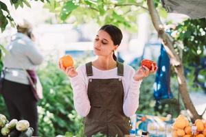 jovem vendedora segurando tomates caseiros nas mãos foto