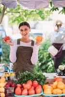 jovem vendedora segurando tomates caseiros nas mãos foto