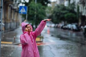 jovem sorridente com capa de chuva enquanto desfruta de um dia chuvoso. foto