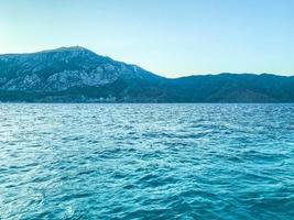 costa. beleza do mar, férias em países quentes. junto ao mar encontram-se altas montanhas com vegetação e arbustos. ondas azuis do mar foto