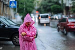 mulher triste em uma capa de chuva na rua na chuva foto