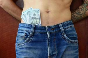 o corpo de um cara de jeans azul com um monte de notas de dólar, visível por baixo das roupas foto