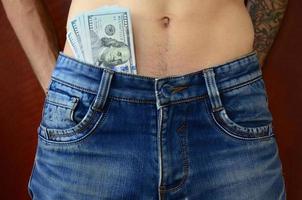 o corpo de um cara de jeans azul com um monte de notas de dólar, visível por baixo das roupas foto