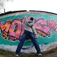 um jovem com um capuz cinza pinta graffiti em rosa e verde c foto