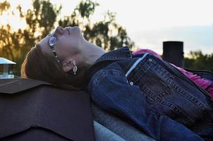 garota de óculos e jaqueta jeans está descansando no telhado de uma casa foto