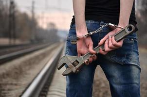 a garota algemada com a chave ajustável no fundo da ferrovia. o conceito de prevenção do crime com a participação da ferrovia e trens. foto