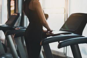 vista traseira do botão iniciar do toque do corredor da mulher do esporte do atleta antes do treino que corre na esteira no clube da aptidão. treino cardio. estilo de vida saudável, mulher treinando na academia. conceito de corrida esportiva. foto