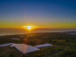 vista aérea do pôr do sol sobre terras agrícolas e mar foto