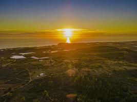 vista aérea do pôr do sol sobre terras agrícolas e mar foto