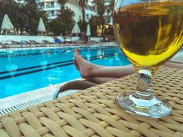 férias no mar na praia. sobre a mesa está um copo com cerveja, uma bebida alcoólica de trigo. a cerveja é derramada em um vidro transparente com uma haste foto