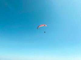 pára-quedistas voam pelo ar. saltar para baixo em um parapente. vista da cidade de uma altura de vôo. pára-quedas vermelho. entretenimento extremo foto