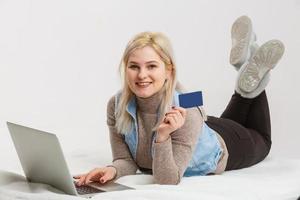 uma mulher feliz segurando um cartão de crédito e fazendo compras na internet foto