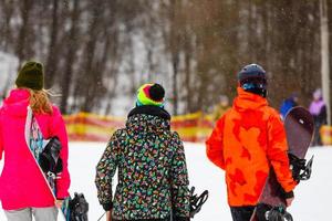 amigos felizes indo nas férias de inverno. jovens se divertindo fazendo snowboard extremo foto