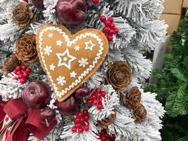 decoração festiva da janela com brinquedos artesanais de natal vintage em forma de coração e flocos de neve contra a janela com uma cortina. decoração de natal para o feriado brinquedos de natal pendurados foto