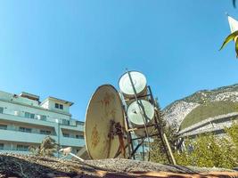 prédio de apartamentos baixo. no telhado da casa existem barris de água para aquecer líquidos. antena redonda e grande para receber canais de televisão foto