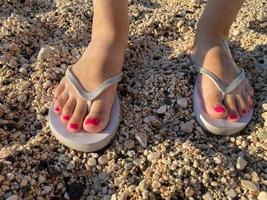 pés femininos com flip-flops unha vermelha foto