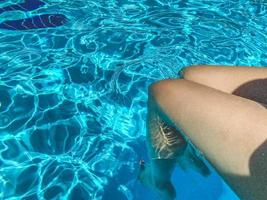 pernas de mulher hispânica relaxando na piscina. foto