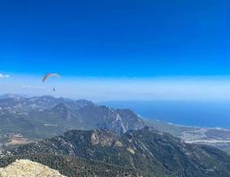 pára-quedistas voam pelo ar. saltar para baixo em um parapente. vista da cidade de uma altura de vôo. parapente com vista para a montanha foto