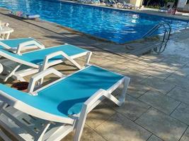 espreguiçadeiras para relaxar e se bronzear com guarda-sóis perto da piscina para nadar e relaxar no hotel de férias em um resort tropical oriental quente paradisíaco foto