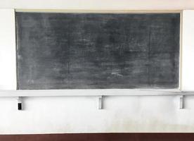 um quadro-negro para giz é montado em uma parede de cimento branco em uma sala de aula em um país pobre da ásia. foto