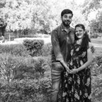 casal indiano posando para ensaio de maternidade. o casal está posando em um gramado com grama verde e a mulher está vacilando sua barriga no jardim lodhi em nova delhi, índia foto