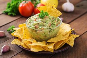 abacate guacamole, limão, tomate, cebola e coentro, servido com nachos - lanche mexicano tradicional foto