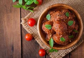 almôndegas em molho de tomate agridoce e manjericão em uma tigela de madeira foto