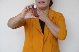 paciente do sexo feminino closeup usa inalador de asma marrom para alívio da asma. conceito, cuidados de saúde em casa. produtos farmacêuticos para tratamento de sintomas de asma ou DPOC. uso sob prescrição. foto
