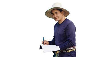 retrato de bonito homem asiático fazendeiro usar chapéu, camisa azul, segure caneta e papel de caderno para escrever algo sobre ele, isolado no fundo branco. conceito, pesquisa agrícola e estudo para desenvolver culturas foto