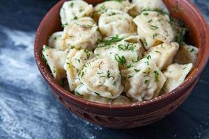 pelmeni russo tradicional ou ravioli, bolinhos com carne em fundo preto de madeira. comida russa e conceito de cozinha russa. foto