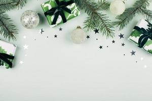 caixas de presente de natal, decorações cinza e galhos de árvores de abeto em fundo verde pastel. configuração plana, vista superior, copie o espaço foto