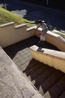 um jovem dá um salto pelo espaço entre os parapeitos de concreto. o atleta pratica parkour, treinando em condições de rua. o conceito de subculturas esportivas entre os jovens foto