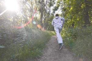 um jovem em um terno esportivo cinza corre ao longo do caminho entre os foto