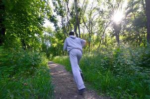 um jovem em um terno esportivo cinza corre ao longo do caminho entre os foto