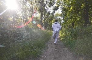 um jovem em um terno esportivo cinza corre ao longo do caminho entre os foto