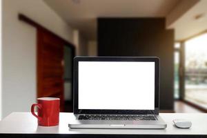 vista frontal da xícara e laptop, smartphone e tablet na mesa no escritório foto