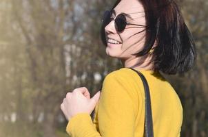 uma garota alegre em um suéter amarelo brilhante caminha pela primavera foto