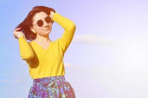 garota morena atraente e fofa em um suéter amarelo contra um foto