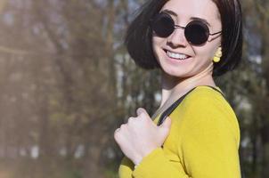 uma garota alegre em um suéter amarelo brilhante caminha pela primavera foto