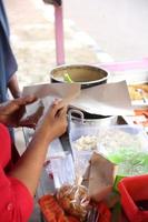 uma velha indonésia está preparando pratos de vegetais para os clientes. foto