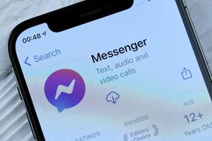 kharkov, ucrânia - 5 de março de 2021 ícone do messenger do facebook e aplicativo da loja de aplicativos na tela de exibição do iphone 12 pro na mesa branca foto