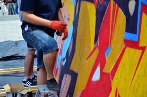 kharkov, ucrânia - 27 de maio de 2017 festival de artes de rua. jovens desenham grafite em paredes de madeira portáteis no centro da cidade. o processo de pintura em paredes com latas de aerossol foto