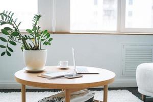 local de trabalho com uma xícara de café, laptop aberto na mesa de madeira no quarto foto