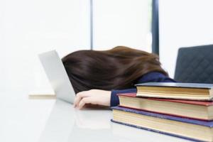 cabelo comprido jovem adormecer na mesa com laptop foto