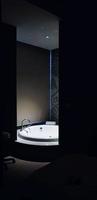 banheira branca com luz no banheiro e primeiro plano escuro. design de interiores e conceito de objeto foto